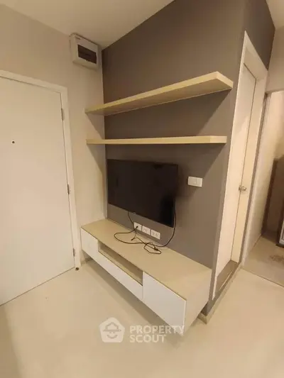 Modern living room with wall-mounted TV and sleek shelving in a stylish apartment.