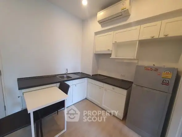 Modern kitchen with sleek countertops and compact dining area in a cozy apartment.