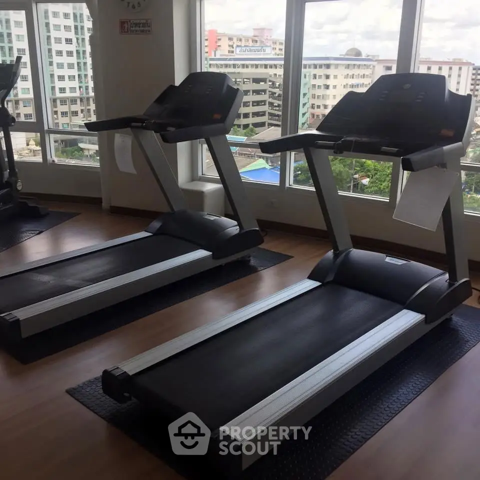 Modern gym with treadmills and city view from large windows