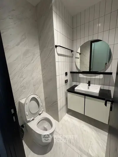 Modern bathroom with sleek design featuring a round mirror and stylish fixtures.