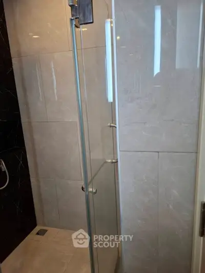 Modern bathroom with sleek glass shower enclosure and marble tiles.