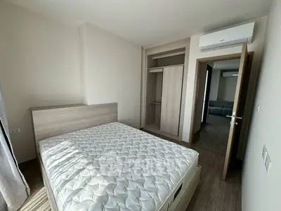 Modern bedroom with wooden flooring and built-in wardrobe, featuring a comfortable bed and air conditioning.