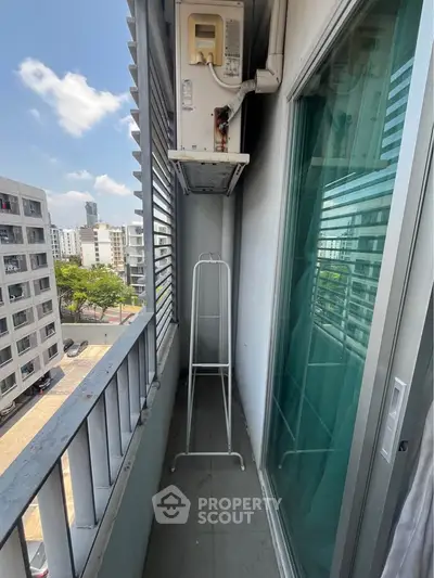 Compact balcony with city view, featuring air conditioning unit and railing, ideal for urban living.