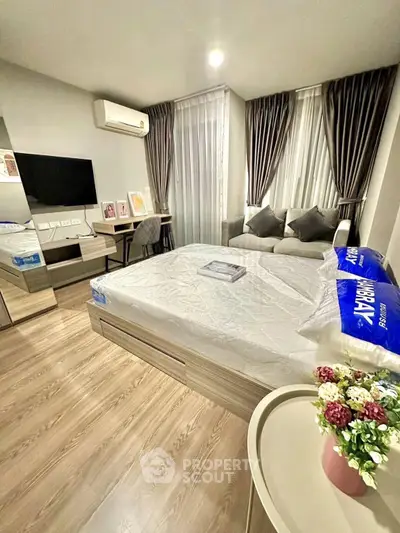 Modern bedroom with stylish decor, featuring a cozy bed, wall-mounted TV, and elegant curtains.