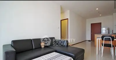 Modern living room with sleek black sofa and open kitchen layout, perfect for contemporary living.