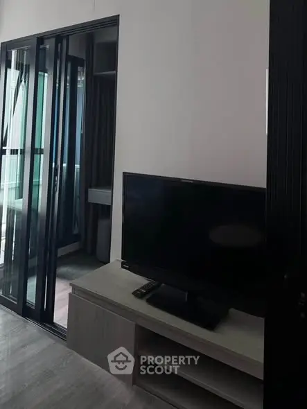 Modern living room with sleek TV setup and glass sliding doors leading to balcony.