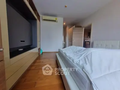 Spacious bedroom with modern design and wooden flooring, featuring built-in storage and air conditioning.