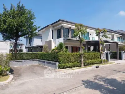 Modern two-story house with lush greenery and spacious driveway in a serene neighborhood.