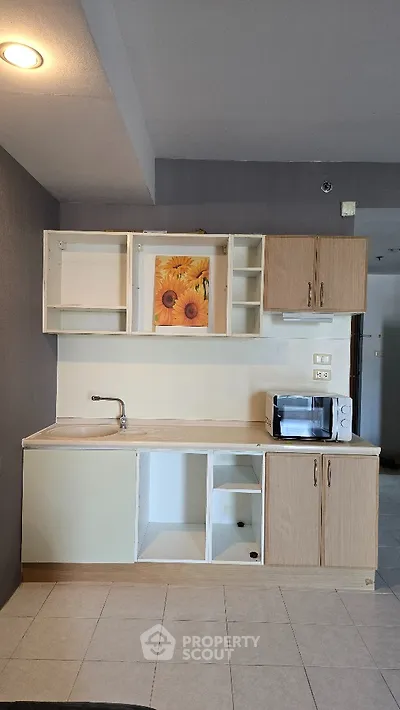 Compact kitchen with open cabinets and microwave in modern apartment