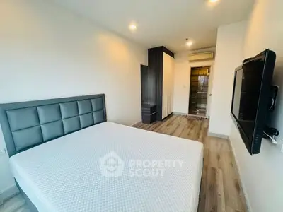 Modern bedroom with stylish headboard and wall-mounted TV in a sleek apartment.