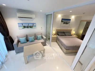 Modern studio apartment with cozy living area and stylish bedroom separated by glass partition.
