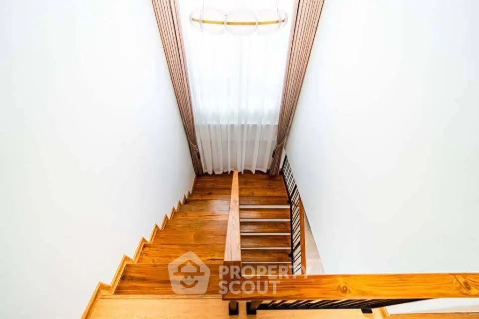Elegant wooden staircase with modern railing in a bright interior space.