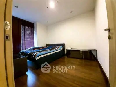 Spacious bedroom with wooden flooring and modern furnishings.