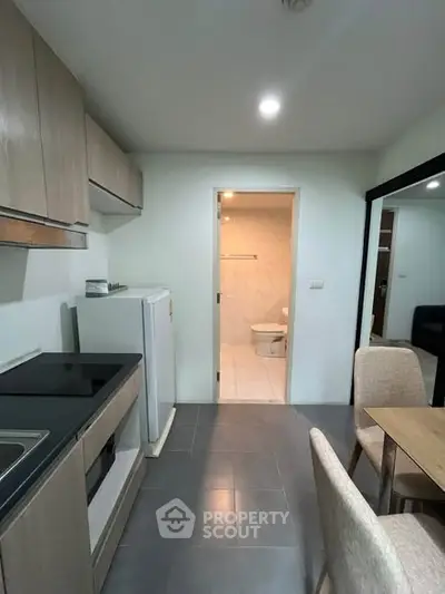 Modern kitchen with sleek cabinets and dining area in cozy apartment