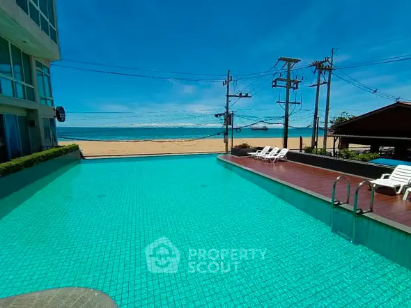 Stunning beachfront pool with ocean view and sun loungers, perfect for relaxation.