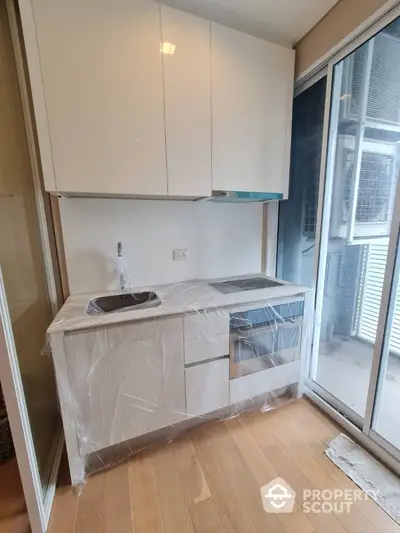 Modern compact kitchen with sleek cabinetry and glass sliding doors for natural light.