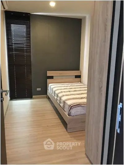 Cozy minimalist bedroom with wooden flooring and modern bed frame, perfect for a serene retreat.