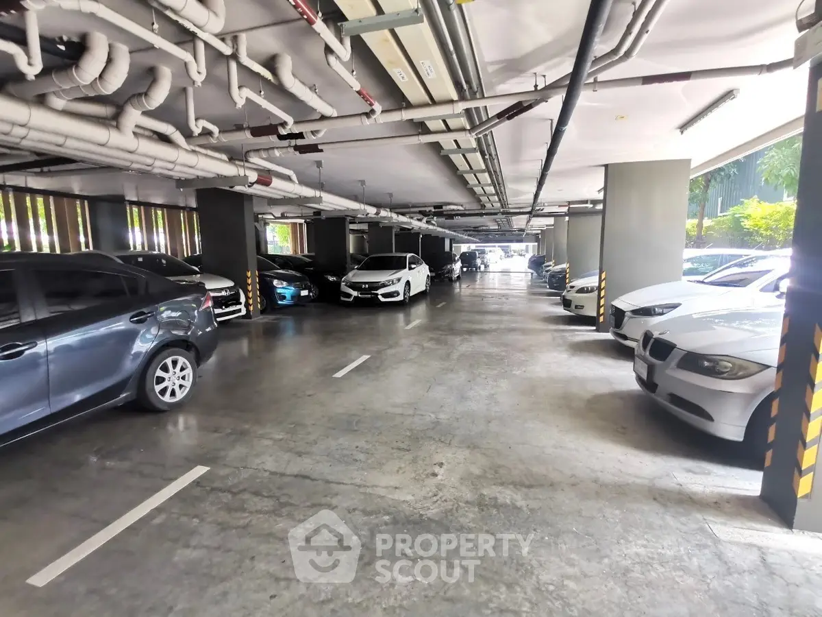 Spacious indoor parking area with multiple parked cars and ample lighting.
