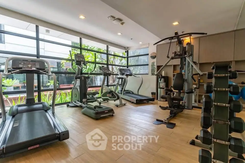 Modern gym with state-of-the-art equipment and large windows in a luxury apartment building.