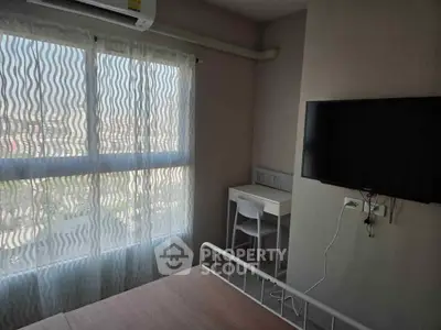 Bright bedroom with large window, modern desk, and wall-mounted TV, perfect for a cozy living space.