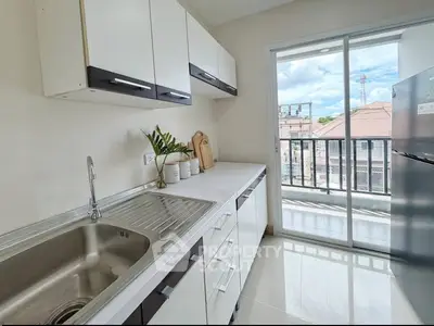 Modern kitchen with sleek cabinets and balcony view in a bright apartment.