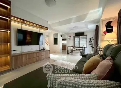 Spacious modern living room with stylish decor and large TV, perfect for relaxation and entertainment.