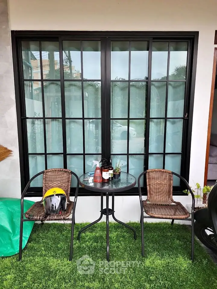 Charming patio with glass table and wicker chairs, perfect for relaxing outdoors.