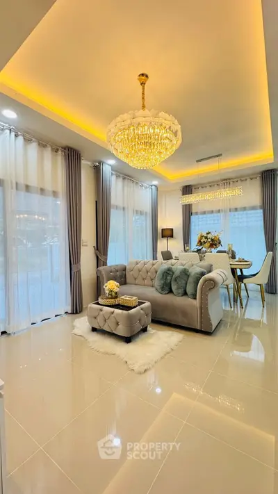 Luxurious living room with elegant chandelier and plush seating in modern open-plan design.