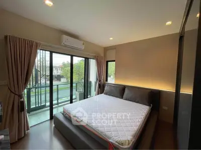 Spacious bedroom with large window and balcony access, featuring modern decor and natural light.