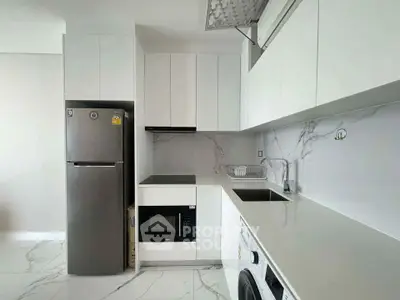 Modern kitchen with sleek white cabinetry, integrated appliances, and marble backsplash.