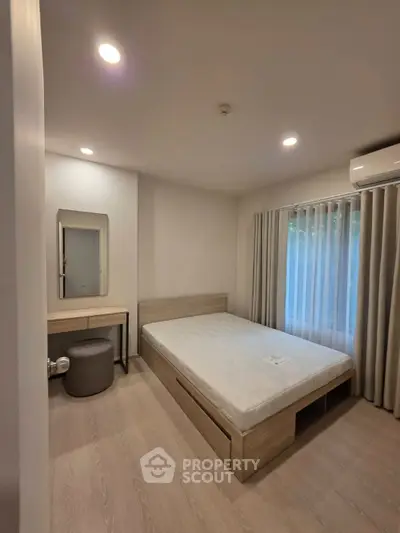 Modern bedroom with minimalist design, featuring a bed, vanity, and natural light from large window.