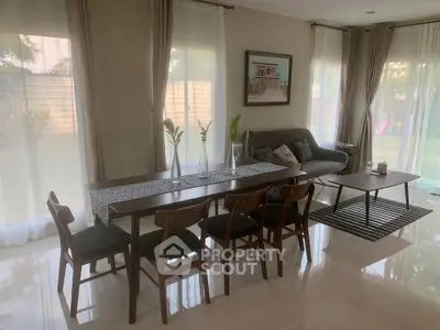 Elegant living room with modern dining set and cozy seating area, large windows offer garden view.