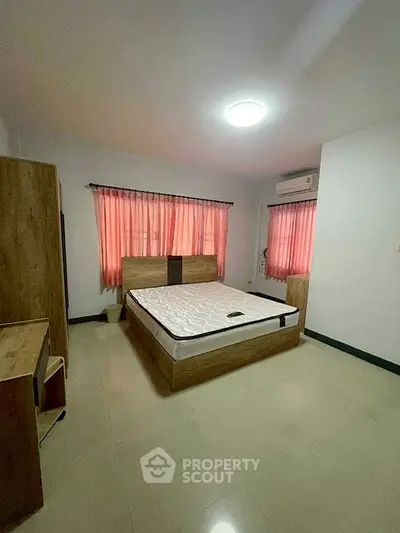 Spacious bedroom with natural light, featuring a comfortable bed and modern furnishings.