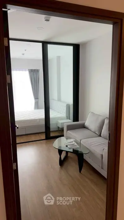 Modern apartment interior with cozy living room and bedroom view, featuring sleek furniture and natural light.