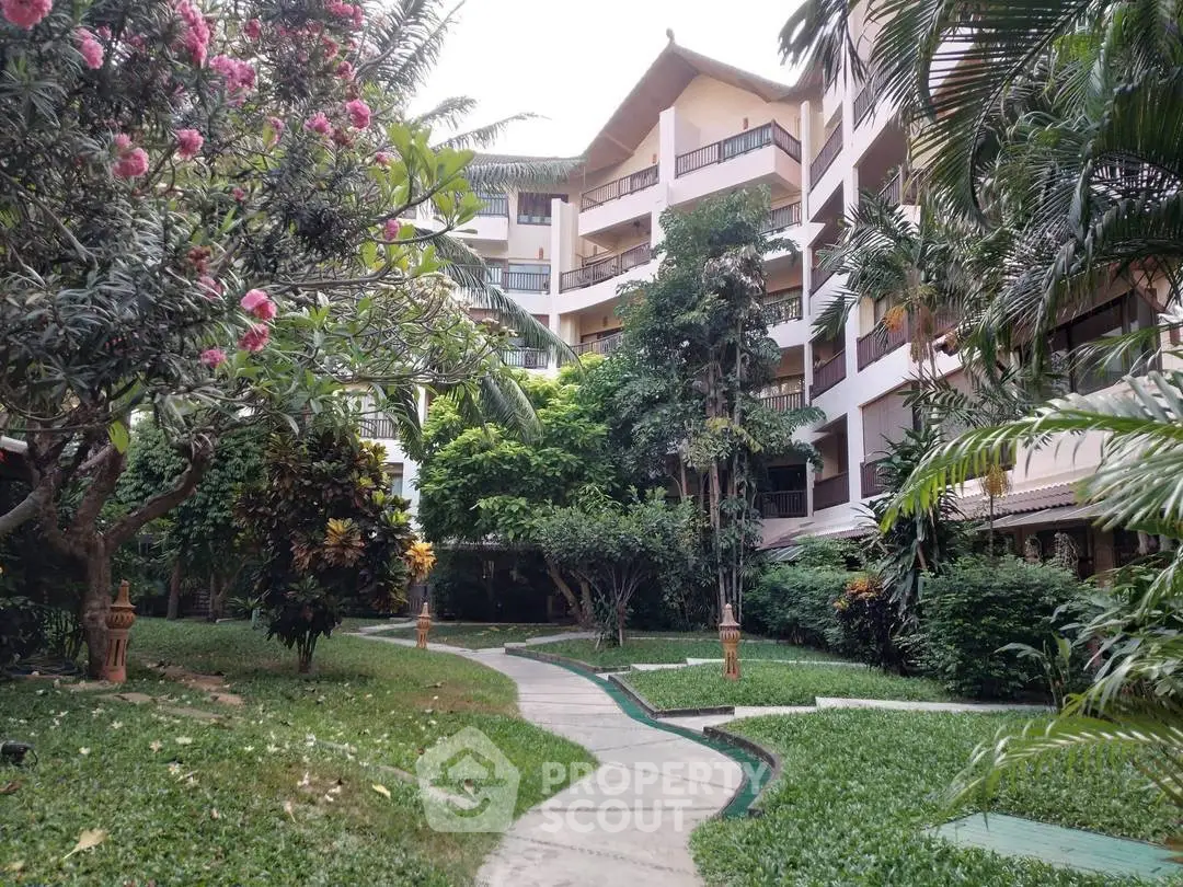 Lush garden view of a modern residential building with tropical landscaping and winding pathways.