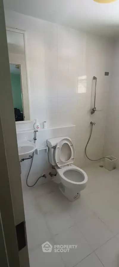 Modern bathroom with white tiles and essential fixtures in a real estate property.