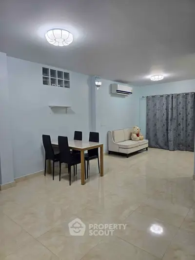 Spacious living room with modern dining set and cozy sofa, ideal for family gatherings.