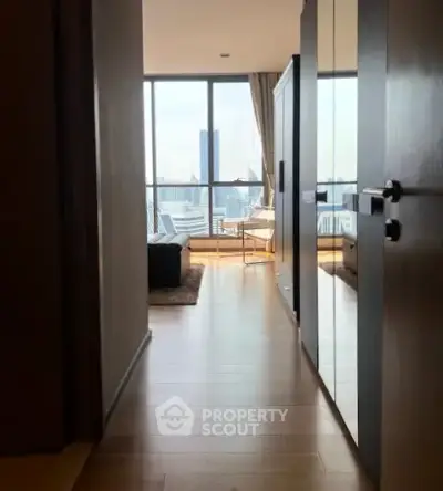 Stylish apartment hallway leading to a bright living room with city view.