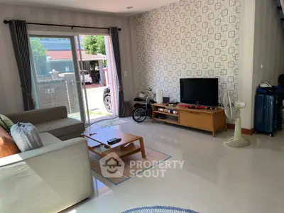 Spacious living room with modern decor and large sliding glass doors opening to a sunny outdoor area.