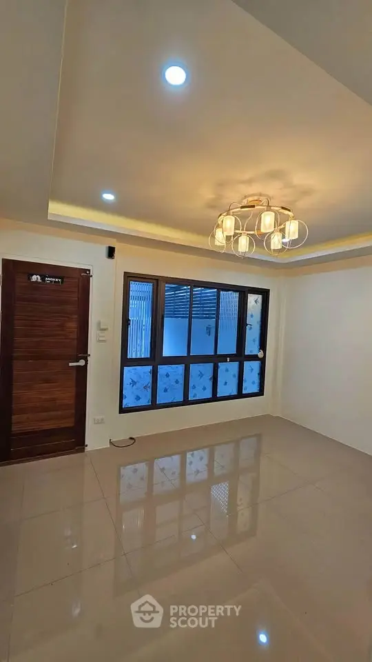 Modern living room with elegant lighting and large window, showcasing a spacious and inviting atmosphere.