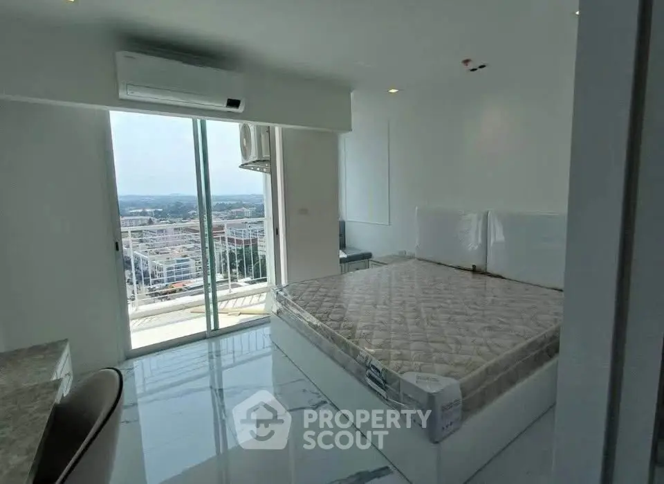 Modern bedroom with balcony view and air conditioning in high-rise apartment.