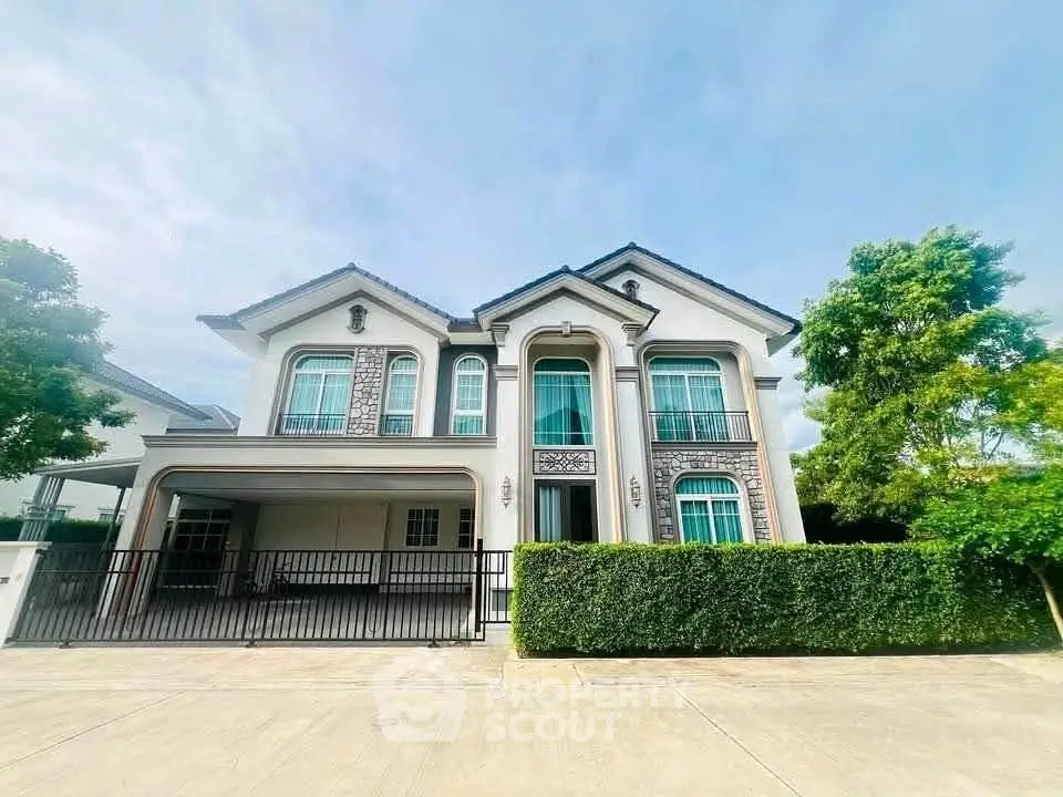 Elegant two-story house with manicured hedges and spacious driveway in a serene neighborhood.