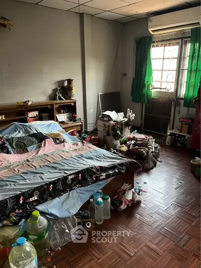 Cozy bedroom with parquet flooring and air conditioning, featuring a large bed and ample natural light.