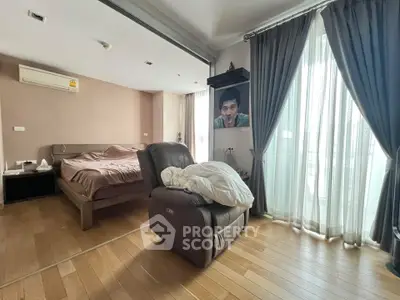 Spacious bedroom with large windows and modern furnishings in a stylish apartment.