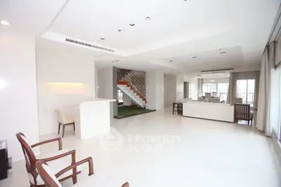 Spacious modern living room with open layout and elegant staircase, perfect for luxury living.