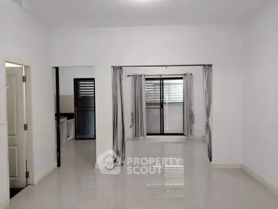 Spacious living room with large windows and glossy tiled floors in modern apartment.