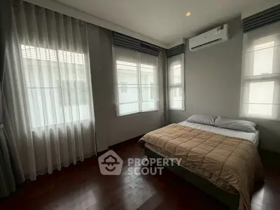 Spacious bedroom with large windows and modern air conditioning unit.