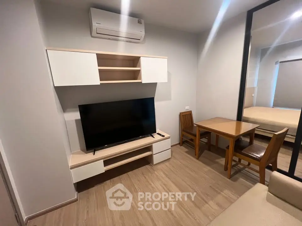 Modern living room with TV, air conditioner, and dining area in cozy apartment.