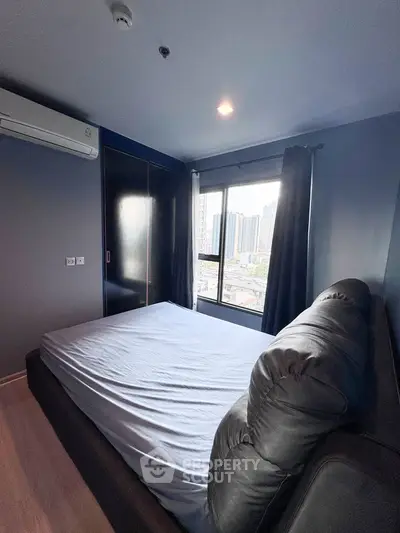 Modern bedroom with city view, featuring sleek design and large window for natural light.