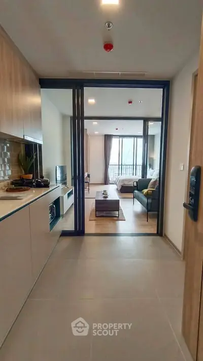 Modern open-layout apartment with sleek kitchen and cozy living area, featuring large windows for natural light.